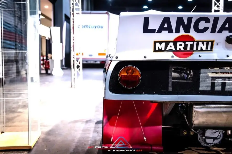 Achterkant van een Lancia 037 in Martini-kleuren op een beurs
