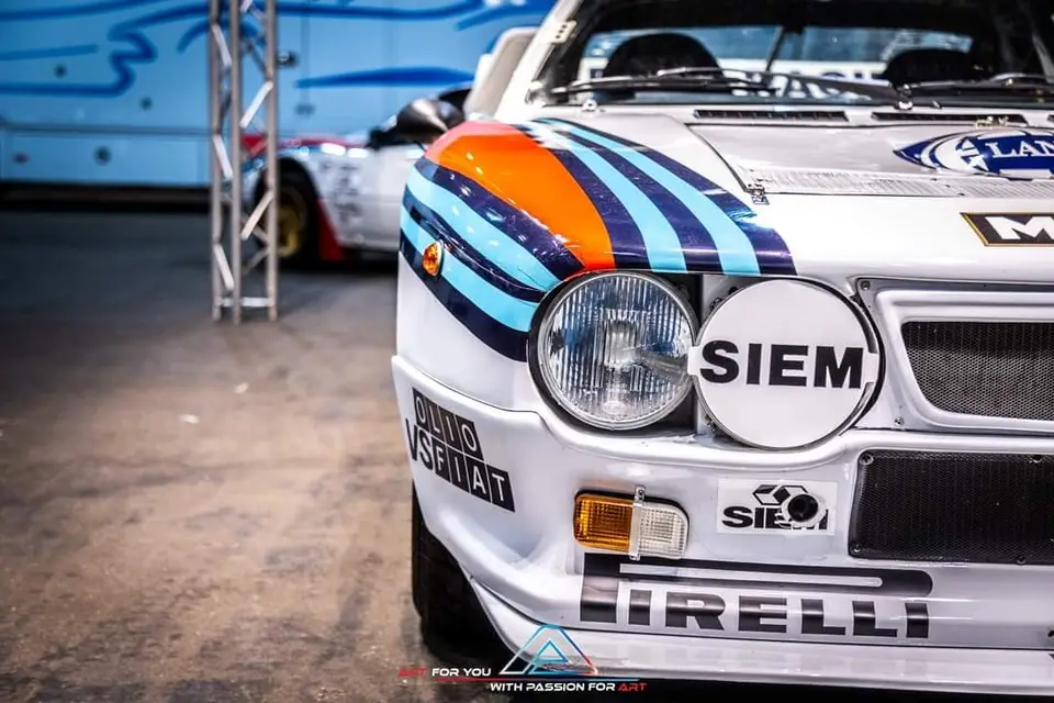 Voorkant van een Lancia 037 in Martini-kleuren op een beurs